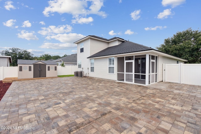 rear view of house with a storage shed, central AC, a patio, and a sunroom