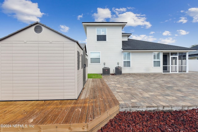 back of property featuring a wooden deck, a patio area, a sunroom, and central AC unit