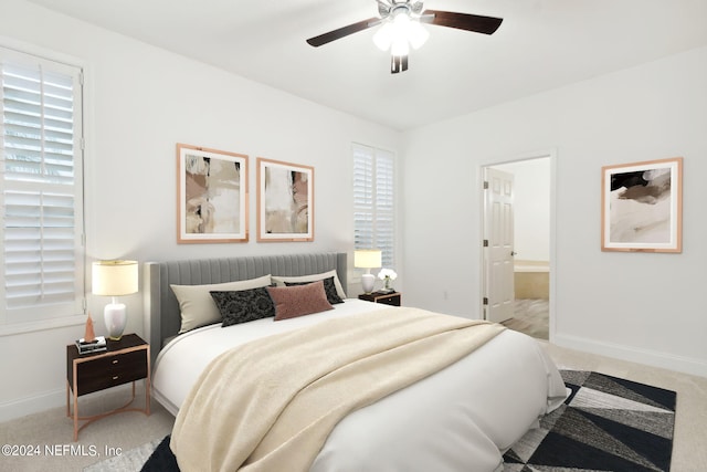 bedroom with ceiling fan, light colored carpet, and ensuite bath