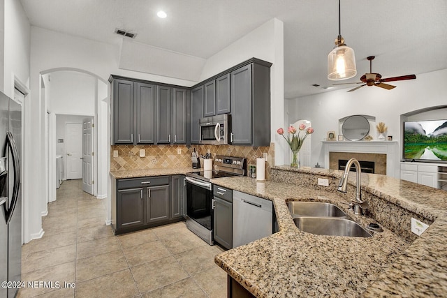 kitchen featuring sink, tasteful backsplash, appliances with stainless steel finishes, kitchen peninsula, and pendant lighting