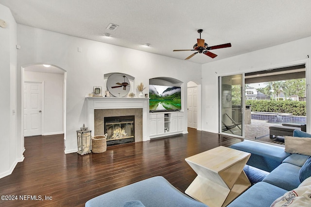 living room with dark hardwood / wood-style floors, ceiling fan, a fireplace, and a textured ceiling