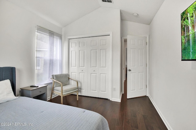 bedroom featuring dark hardwood / wood-style floors, vaulted ceiling, and a closet