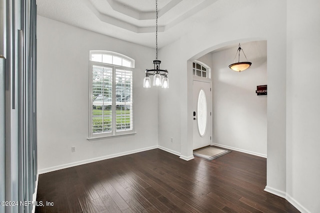 foyer entrance with a chandelier, dark hardwood / wood-style flooring, and a tray ceiling