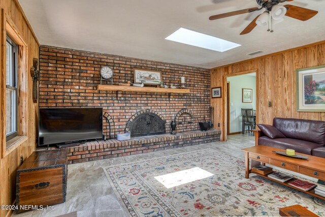 living room with wood walls, brick wall, a skylight, and ceiling fan