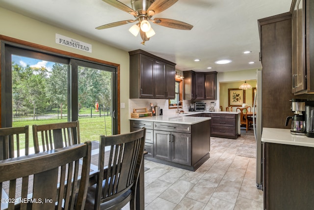 kitchen featuring light tile patterned flooring, tasteful backsplash, dark brown cabinets, ceiling fan, and sink