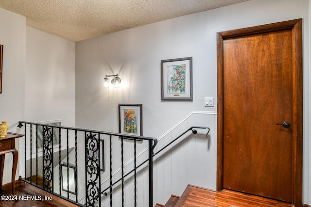 staircase with a textured ceiling and hardwood / wood-style floors