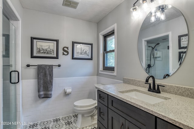 bathroom with vanity, tile walls, a shower with shower door, toilet, and tile patterned flooring