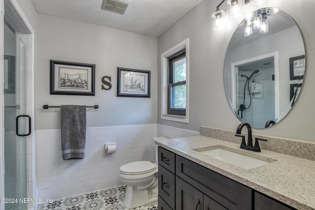 bathroom featuring toilet, a tile shower, visible vents, and tile walls