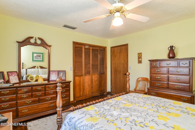 bedroom with dark wood-type flooring, a textured ceiling, ceiling fan, and a closet