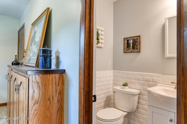 bathroom with vanity, decorative backsplash, toilet, and tile walls