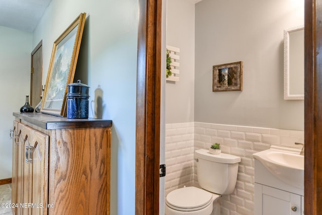 bathroom featuring tile walls, wainscoting, vanity, and toilet