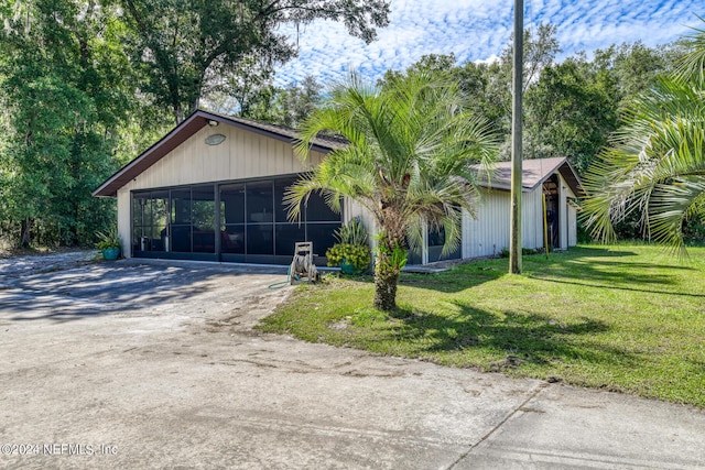 view of front of home with driveway, a sunroom, and a front yard