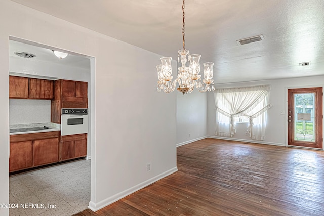 unfurnished dining area with a chandelier, light hardwood / wood-style floors, and a textured ceiling