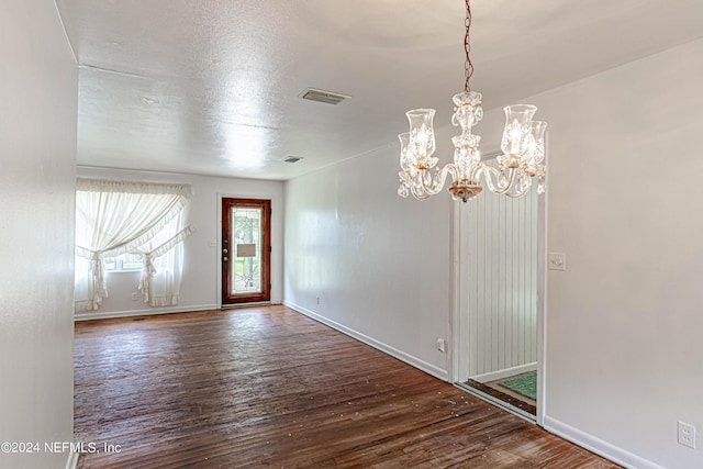 foyer featuring baseboards, visible vents, wood finished floors, an inviting chandelier, and a textured ceiling