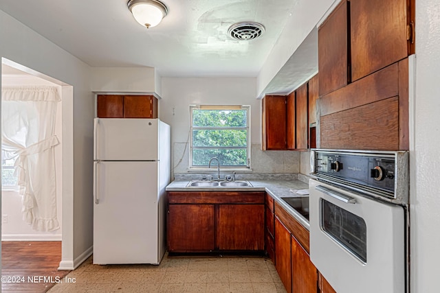 kitchen featuring white appliances, visible vents, a sink, light floors, and backsplash