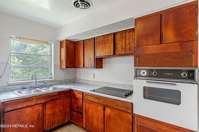 kitchen featuring black electric stovetop, a sink, visible vents, light countertops, and white oven