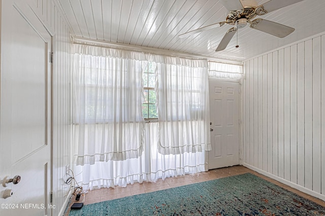 empty room featuring wood ceiling, ceiling fan, and wooden walls