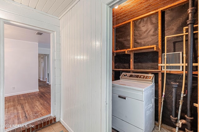 laundry room with laundry area, wood walls, wood finished floors, visible vents, and washer / clothes dryer