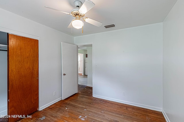 unfurnished bedroom featuring a closet, visible vents, a ceiling fan, wood finished floors, and baseboards