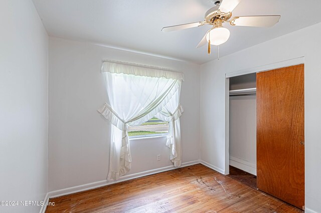 unfurnished bedroom with ceiling fan, hardwood / wood-style flooring, and a closet