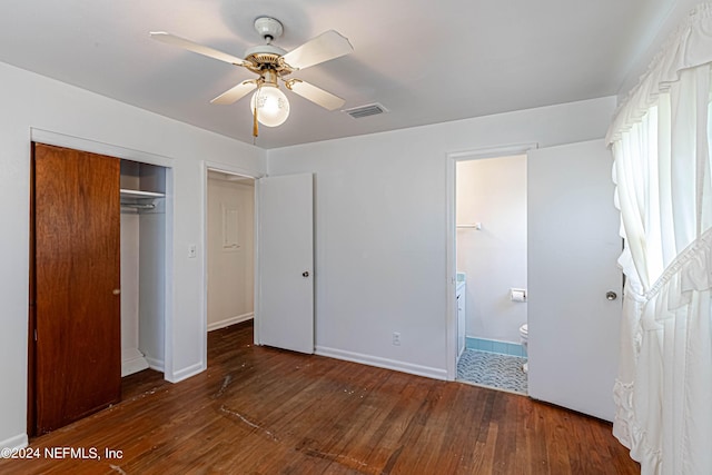 unfurnished bedroom featuring a closet, ceiling fan, dark wood-type flooring, and ensuite bath