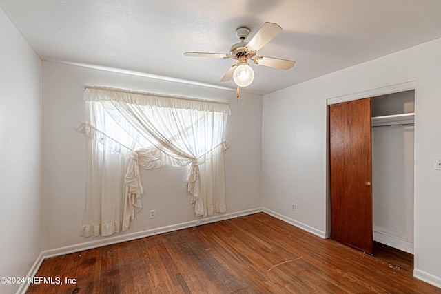 unfurnished bedroom featuring a ceiling fan, a closet, hardwood / wood-style flooring, and baseboards