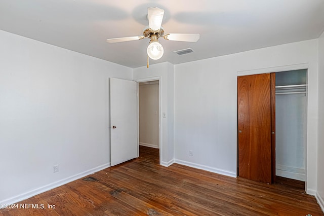 unfurnished bedroom with a closet, visible vents, ceiling fan, wood finished floors, and baseboards