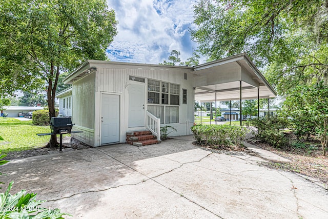 rear view of house with entry steps, a lawn, and concrete driveway