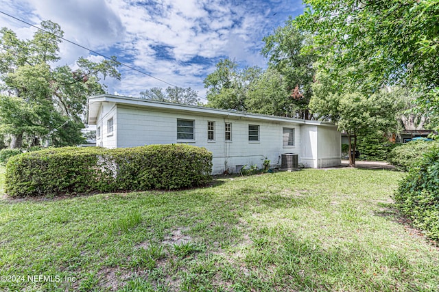 back of house with central air condition unit and a lawn