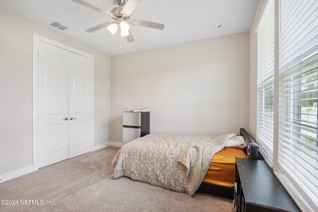 carpeted bedroom with stainless steel fridge, ceiling fan, and a closet