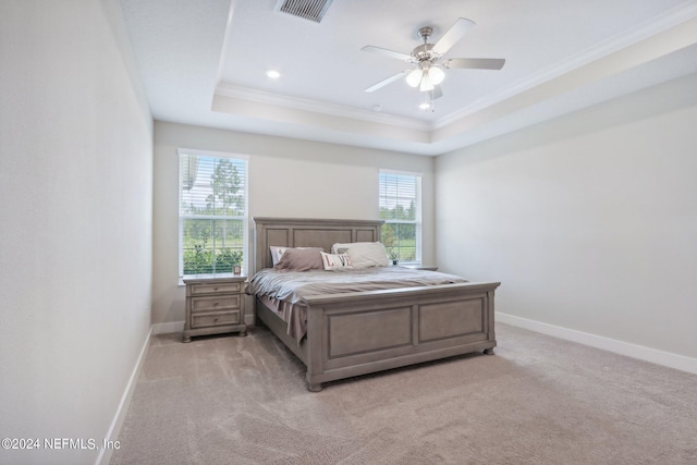 carpeted bedroom featuring a tray ceiling, ornamental molding, and ceiling fan