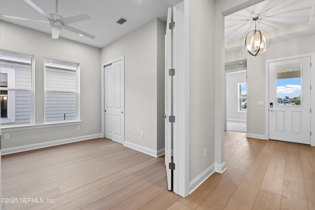 foyer entrance with ceiling fan with notable chandelier and light hardwood / wood-style floors