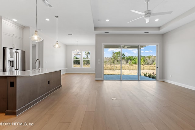 kitchen with a large island, hanging light fixtures, a tray ceiling, light hardwood / wood-style floors, and high end refrigerator