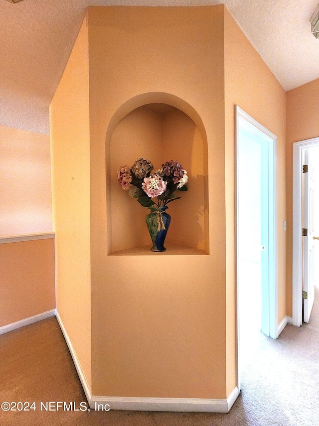 corridor featuring a textured ceiling and carpet floors