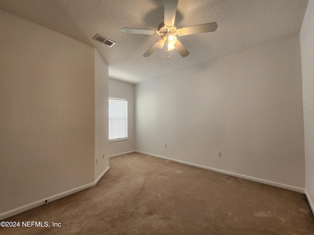 spare room featuring a textured ceiling, ceiling fan, and carpet