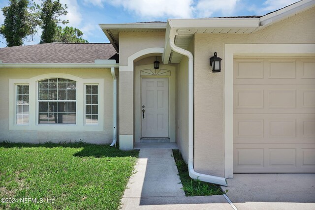 entrance to property featuring a yard and a garage