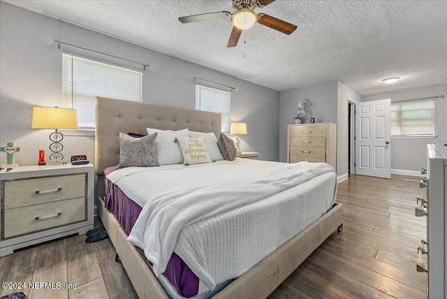 bedroom with dark hardwood / wood-style flooring, ceiling fan, and a textured ceiling