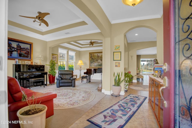 tiled living room with a tray ceiling, ceiling fan, and crown molding