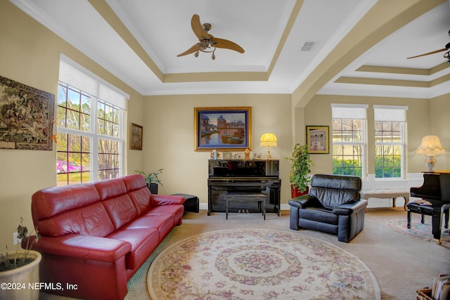 carpeted living room with a healthy amount of sunlight, ceiling fan, crown molding, and a tray ceiling