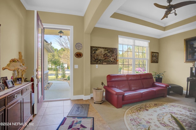 living room with a raised ceiling, crown molding, light tile patterned floors, and ceiling fan