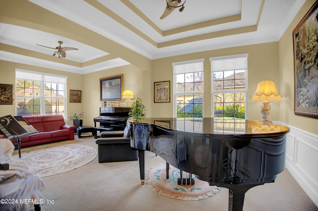 living room with carpet floors, ceiling fan, a raised ceiling, and ornamental molding