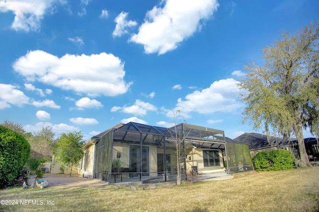 rear view of house featuring a patio, a lawn, and a lanai