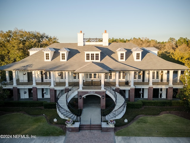 view of front of house featuring a balcony and a front lawn