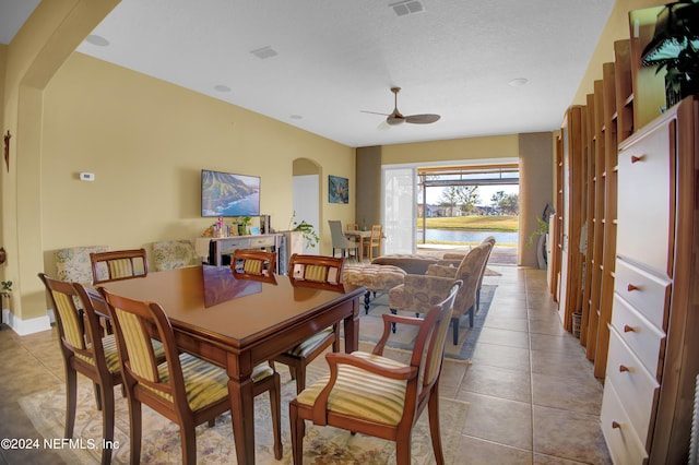 dining area featuring a textured ceiling, light tile patterned floors, and ceiling fan