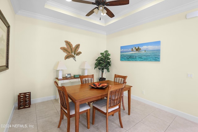 dining room with ornamental molding, light tile patterned floors, ceiling fan, and a tray ceiling