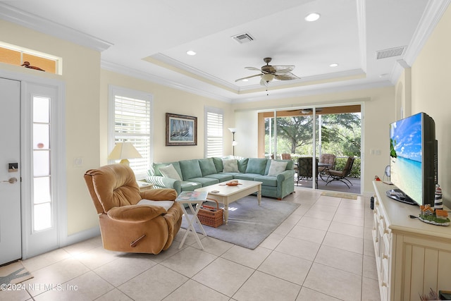 tiled living room featuring a raised ceiling, ornamental molding, and ceiling fan