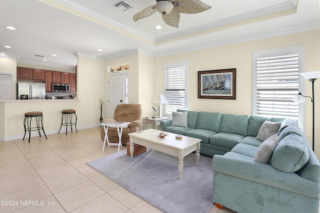 tiled living room with ornamental molding, a raised ceiling, and ceiling fan