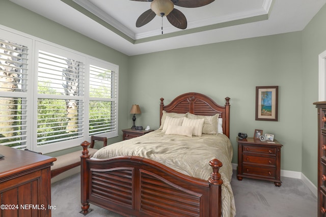 carpeted bedroom with a raised ceiling, ornamental molding, and ceiling fan