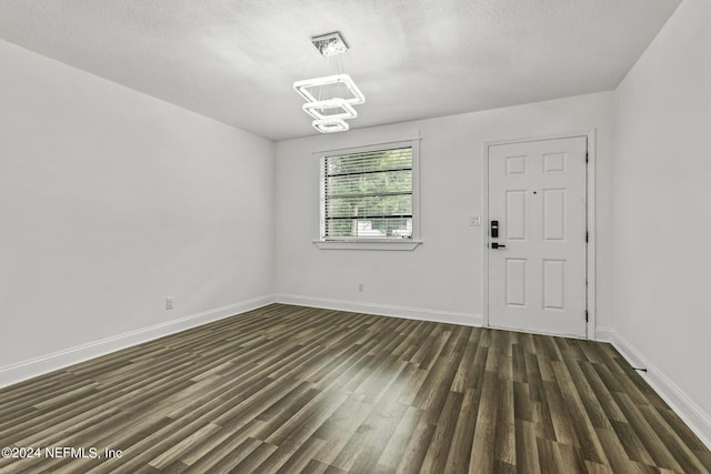 interior space featuring dark wood-type flooring, a chandelier, and a textured ceiling