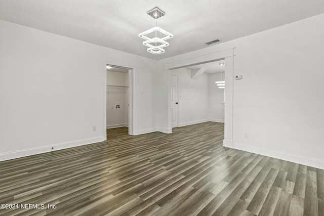 spare room featuring an inviting chandelier and dark hardwood / wood-style flooring